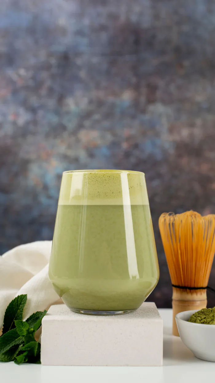 Matcha latte servido junto a un batidor
